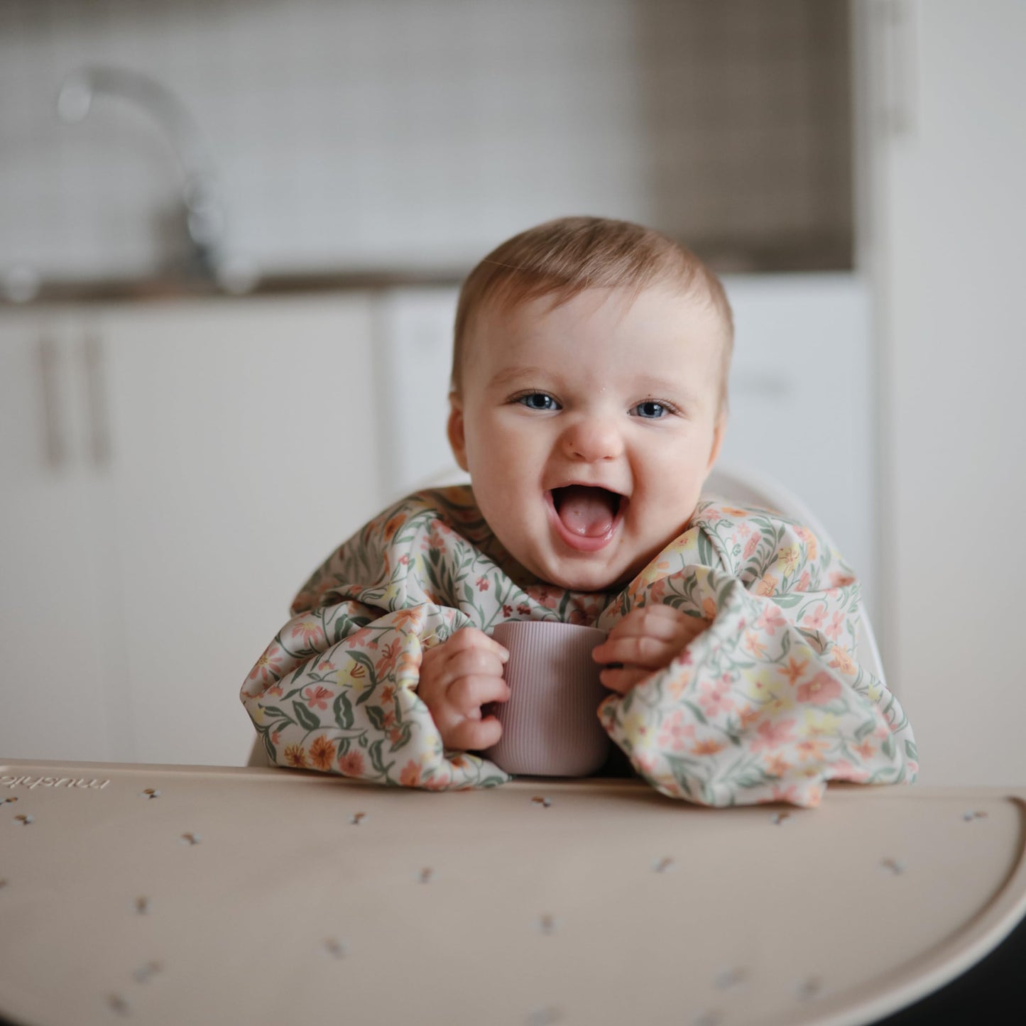 mushie Long Sleeve Baby Bib | Water Resistant Adjustable Fit for Ages 6-24 Months (Pastel Blooms)